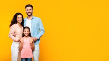 Sevgi dolu bir aile. Avrupalı anne ve baba kızlarıyla poz veriyor sarı arka planda, panoramada, boş alanda izole edilmiş. Birliktelik ve bağlanma kavramı