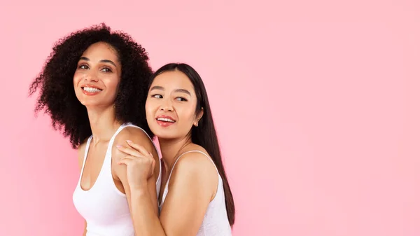 Diversity and natural beauty care. Two young multiracial women posing isolated on pink background, panorama with free space, web banner, place for ad