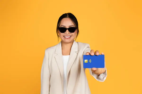 Uśmiechnięta Młoda Azjatka Garniturze Okularach Pokazuje Kartę Kredytową Odizolowaną Żółtym — Zdjęcie stockowe