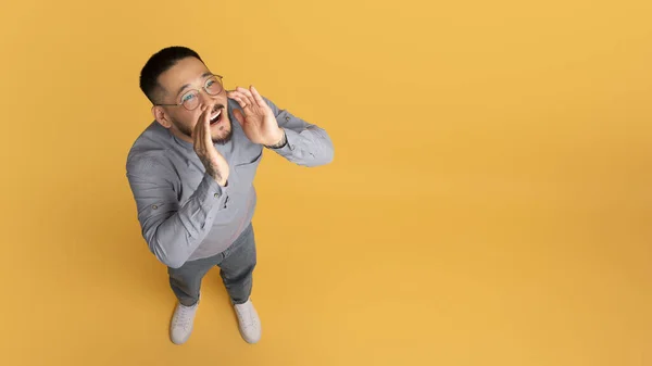 兴奋的年轻亚洲人 手拉手靠近嘴宣布 快乐的千年男性共享新闻或信息而站在黄色工作室背景 复制空间 — 图库照片