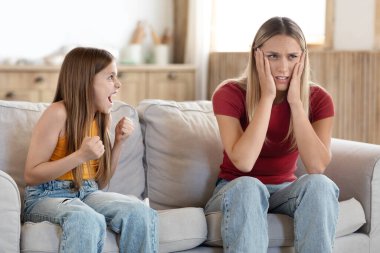 Yorgun kadın, anne başını okşar. Çığlık atan inatçı kız çocuk yüzünden çaresiz hisseder. Sinirli anne, yaramaz, zor kız çocuğu yaramazlığı yüzünden stres yapar.