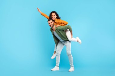 Yakışıklı bir adam, mavi stüdyo geçmişine karşı karısını sırtında taşıyor. Uzun bir portre, boş alan. Heyecanlı çift eğleniyor, birlikte romantik zaman geçiriyorlar.