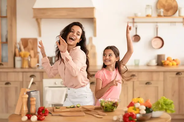 Cooking Fun. Mommy And Daughter Kid Fooling While Preparing Dinner Together, Dancing And Singing In Modern Kitchen At Home, Making Salad And Fresh Vegetable Meals. Family Nutrition, Recipes