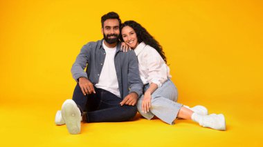 Neşeli Arap Genç Eşler Stüdyo Zeminde Birlikte Otururken, Sarı Arkaplan, Panorama 'daki Kamera Pozisyonuna Gülümsüyor. Romantik İlişki Kavramında Aşk ve Mutluluk