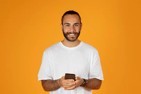 在智能手机上聊天 用社交网络应用 在橙色工作室背景下隔离 微笑着留着白胡子的欧洲裔成年人 远程学习 广告和提供 有趣的视频 — 图库照片