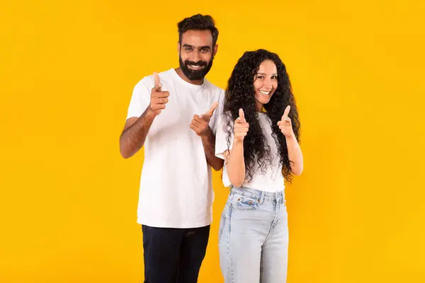 あなたを見てください ポジティブな中東の若いカップルは 笑顔でカメラを見ている指を指し 黄色の背景をポーズし あなたのために素晴らしいオファーを選択し 広告します あなたは次のコンセプト — ストック写真