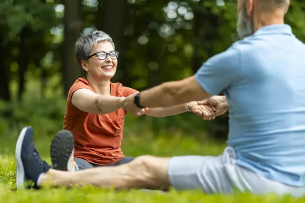 Sport Activities For Seniors. Portrait Of Older Couple Training Together Outdoors, Happy Mature Man And Woman Exercising In Park, Stretching Arms And Smiling To Each Other, Enjoying Healthy Lifestyle