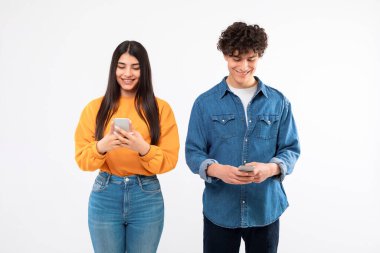Akıllı telefonlu neşeli genç çift pozu, Beyaz Stüdyo geçmişiyle ilgili sosyal medya uygulamalarında mesajlaşmalar. Modern cep telefonları vasıtasıyla internette sörf yapan kız arkadaş ve erkek arkadaş