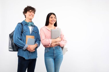 Üniversite Teklifi. Sırt çantası, dizüstü bilgisayarı ve not defterleriyle beyaz stüdyo arkaplanına bakan Avrupalı genç bir çift mesaj için boş alan arıyor. Eğitim ve Bilgi