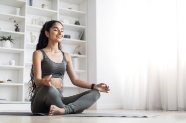 Stres atma, yoga, meditasyon, farkındalık konsepti. Nilüfer çiçekli güzel Hintli kadın evde poz veriyor yoga yapıyor, meditasyon yapıyor, fotokopi çekiyor.