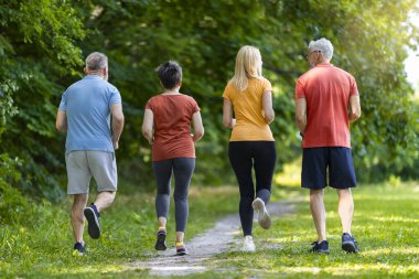 Spor kıyafetli yaşlı insanların dışarıda koşuşunun, yeşil parkta koşuşan yaşlı erkek ve kadınların, dışarıda antrenmanların keyfini çıkaran olgun arkadaşların, boş alanla uzun pozlarının arka plan görüntüsü.