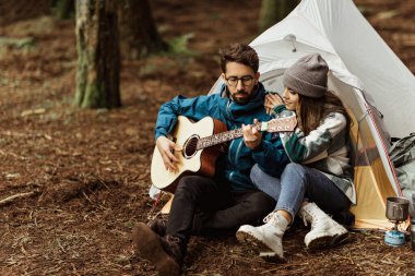 İyi ki beyaz ceketli genç bir çift çadırın yanında oturup gitar çalıyor, müzik dinliyor, boş zamanlarında macera yaşıyor ve sonbaharda soğuk ormanda hafta sonu geçiriyor. İlişki, birlikte tatil, yaşam tarzı.