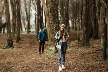 Sırt çantalı, beyaz ceketli olumlu genç bir aile birlikte maceranın tadını çıkarıyorlar, serbest zaman yürüyüşü, sonbaharda soğuk ormandaki fotokopi alanına bakıyorlar, tam boy. Hafta sonu, tatilde aktif yaşam tarzı