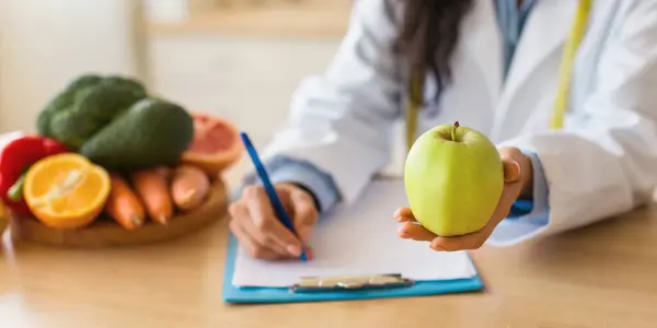 Female Doctor Making Prescription Writing Diet Plan Holding Green Apple — Stock Photo, Image