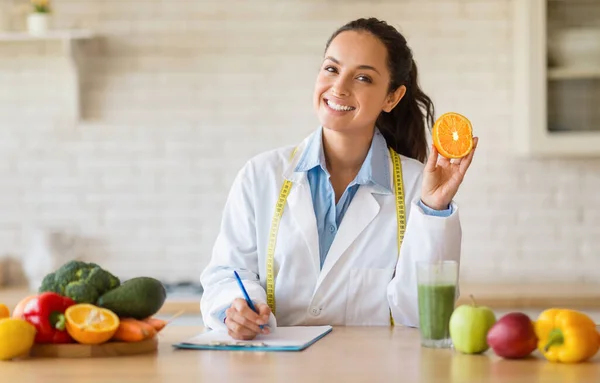 Felice Consigliere Nutrizionale Femminile Possesso Frutta Arancione Rendendo Piano Pasto — Foto Stock