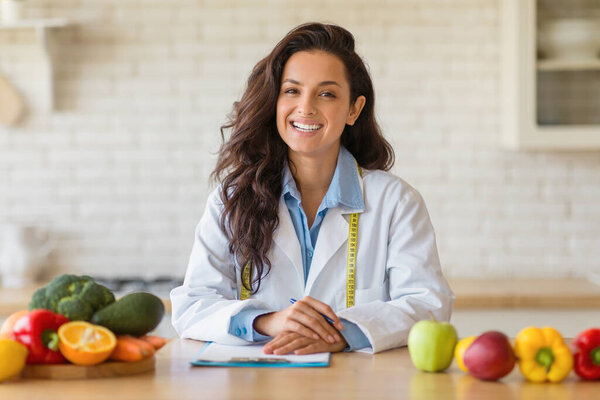 Portrait of friendly female weight loss consultant smiling at camera in modern clinic, woman dietitian recommending plant based healthy meal plan, free space