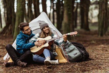 Ceketli mutlu genç beyaz adam karısına gitar çalma dersi veriyor, çadırın yanında oturuyor, müziğin keyfini çıkarıyor, sonbaharda soğuk ormanda boş vakitlerin tadını çıkarıyor. Hafta sonu, aşk, ilişki tatili ve seyahat.