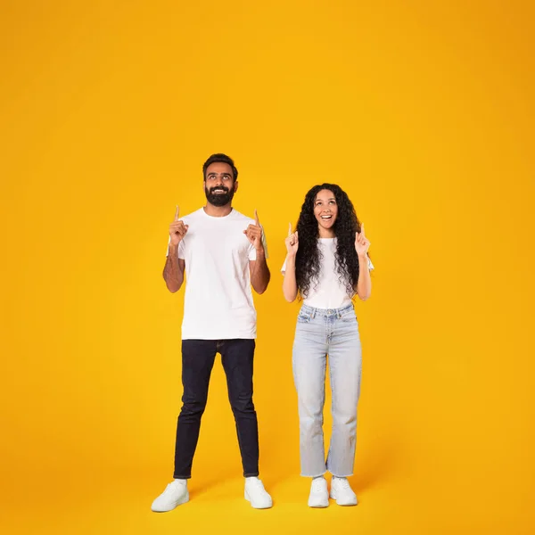 エキサイティングな中東の配偶者は両手で指を指差し 頭の上のテキストのための無料のコピースペースを示し 黄色のスタジオの背景にポーズ 素晴らしいオファーコンセプト — ストック写真