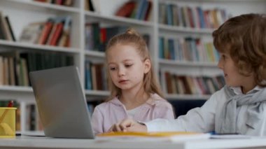 Eğitim kavramı için modern teknolojiler. Düşünceli çocuk ve kız laptopta birlikte test çözme, cevabı seçme ve başarıyı kutlama, beşlik çakma, çekimin izini sürme, yavaş çekim