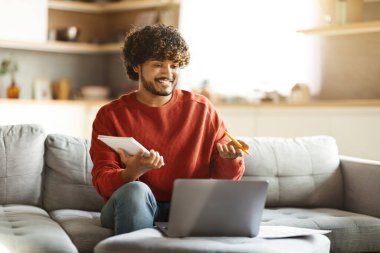 Çevrimiçi Öğretmenlik. Genç Hintli adam evdeki dizüstü bilgisayarında telekonferans yoluyla ders veriyor, neşeli Doğu erkek özel hocası öğrenci ile görüntülü görüşme yapıyor, web kamerasında konuşuyor ve el kol hareketi yapıyor.