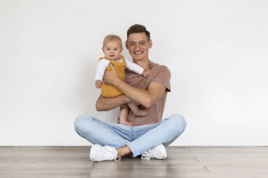 Baba ve Çocuk. Mutlu, genç bir baba, birlikte poz verirken, evde oturup, milenyum babasını severken, kameraya bakıp gülümserken, uzayın fotokopisini çekerken, tatlı bir erkek çocuğu kucaklıyor.