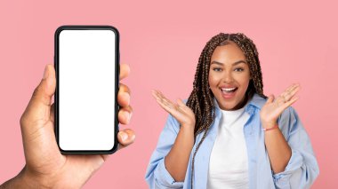 Heyecanlı sürpriz siyah milenyum aşırı kilolu bayanın bağırışları, yüzün yanında el ele tutuşması, boş ekranlı telefon, pembe stüdyo arka planında izole edilmiş. Wow uygulama, kazan