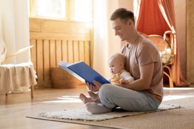 Babalık iznini iptal et. Küçük babasının sevimli oğluna kitap okuması oturma odasında dinlenirken, babasının evde bebekle mutlu bir bağ kurması, boşluğu kopyalaması.