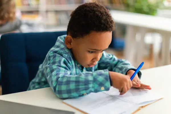 Focused Black Schoolboy Writing His Copybook Lesson Primary Classroom Reflecting — Stock Photo, Image