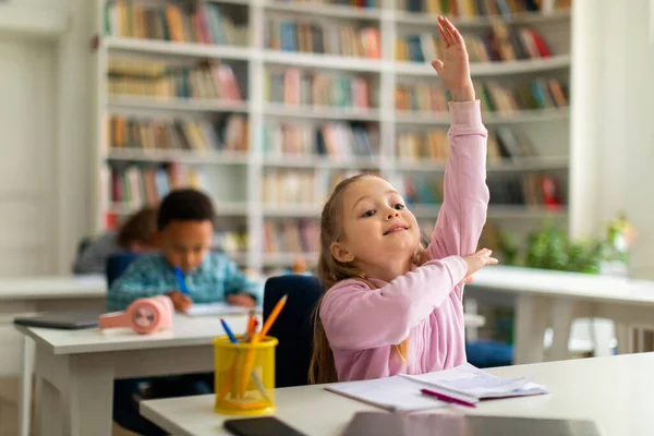 Attentive Schoolgirl Seated Her Desk Primary Classroom Raises Her Hand — Stock Photo, Image