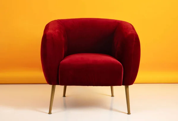 Red comfort armchair on floor on yellow wall background on free space, nobody, close up. Modern cozy interior, minimalist design, home furniture, ad and offer, visual appeal
