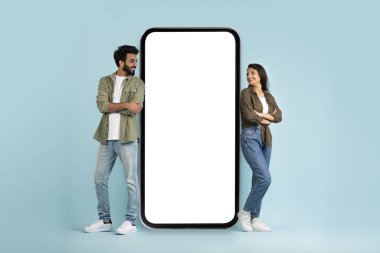 Gezici flört uygulaması. Bin yıllık çok kültürlü kadın ve erkek, reklam için beyaz ekran modeliyle büyük telefonun başında duruyor, birbirlerine bakıyor ve gülümsüyor, boşluğu kopyalıyor.