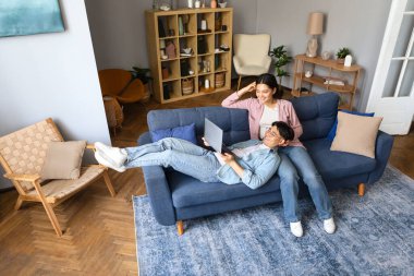 Japon eşler dizüstü bilgisayarlarında video izlemeyi seviyorlar, evdeki konforlu oturma odasında kanepede dinleniyorlar. Çevrimiçi teknoloji ve aile bilgisayar keyfi