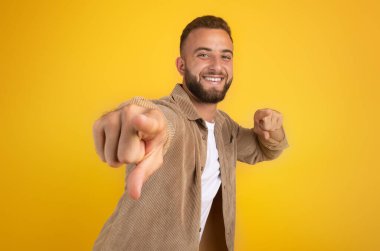 Sakallı, kameraya işaret eden, tavsiye edilen, turuncu arka planda izole edilmiş bin yıllık beyaz bir adam. Güven, senin seçimin, dön, motivasyon jesti