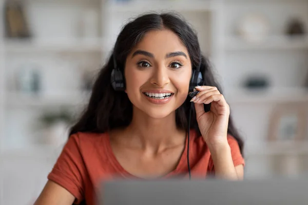 Video Conference, Telecommunication. Smiling young indian woman having web call on laptop at home office. Portrait of friendly cheerful eastern lady have video chat with client, using headset