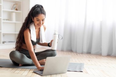 Çevrimiçi Egzersiz Maratonu, Uzaktan Eğitim. Bin yıllık Hintli kadın mindere oturup koçla konuşuyor öğretmenle görüntülü görüşme yapıyor, sanal idman içme suyuna ara veriyor.