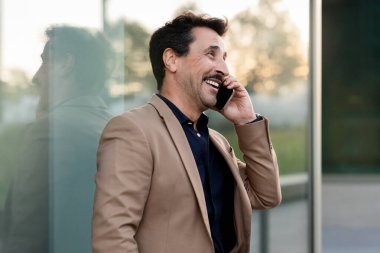 Yakışıklı orta yaşlı profesyonel erkek menajer şehir ortamında rahatça gezinirken önemli bir iş görüşmesine katılmış, kopyalama alanına bakıyor. İş hayatında iletişim