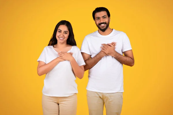 Loving Couple Placing Hands Chest Heart Isolated Yellow Studio Background — Stock Photo, Image