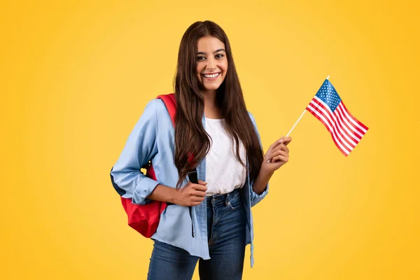 ポジティブな慎重な十代の学生の女性は 米国の旗と 愛国心と学界を組み合わせ 黄色の背景に隔離されています ライフスタイル 国家プライド 交換学習 英語学習 — ストック写真