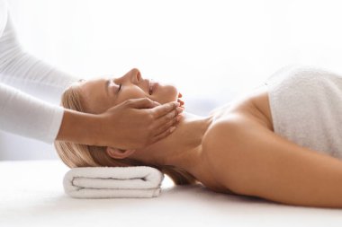 Güzellik Hizmetleri. Lüks spa salonunda profesyonel yüz gerdirme masajı alan orta yaşlı mutlu bir kadın, rahatlamış olgun bir kadın sağlığın tadını çıkarıyor, zevk ve sükunet anı sergiliyor.