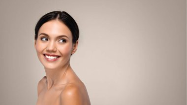 Güzel beyaz bir bayanın arkasına bakmasına, güzellik bakımının keyfini çıkarmasına, gri stüdyo arka planında izole edilmesine, panorama yapmasına sevindim. Spa prosedürleri, yaşam tarzı, canlılık ve kaldırma tedavisi, reklam ve teklif