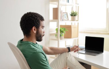 Evde uzaktan çalışan dizüstü bilgisayarlı genç bir ortadoğulu blogcu ya da yönetici, aydınlık oda ofis içinde video çağrısı yapıyor. İş, öğrenim, başlangıç web sitesi