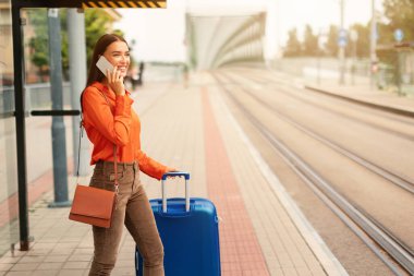 Şehir tramvay durağında cep telefonuyla konuşan bir kadın. Havaalanına giderken bavullu genç bir yolcunun telefonla konuşması. İletişim ve iş seyahati. Boşluğu kopyala