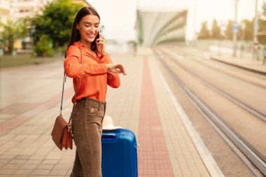 Saatine bakan bir bayan telefonda konuşuyor, tramvayın şehre gelişini bekliyor, şehir merkezindeki bir tramvay durağında bavulla tek başına duruyor. Gidiş-dönüş ve ulaşım zaman çizelgeleri