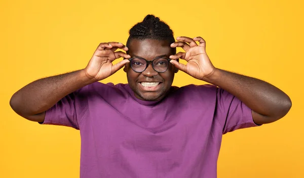 快乐而又多姿多彩的黑人通过黄色背景的镜片看相机 兴奋的男人带着眼镜兴奋的演播室 对好消息的反应或提供的服务 — 图库照片