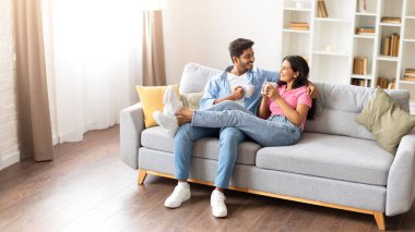 Rahat Hintli çift öğleden sonralarını kanepede kahve içerek geçirir. Bu sakin, samimi anı paylaşırken evlerinin etrafını sararlar..