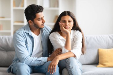 Sevgi dolu Hintli bir adam üzgün karısını sakinleştiriyor, oturma odasındaki kanepesinde oturuyor, hassas bir ortamda şefkatli, şefkatli bir hava yayıyor.