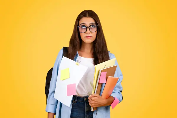 忧郁疲惫的欧洲少女 带着书本 身兼多项任务 许多工作和功课 被黄色背景隔离 工作室 学生生活方式 教育问题 — 图库照片