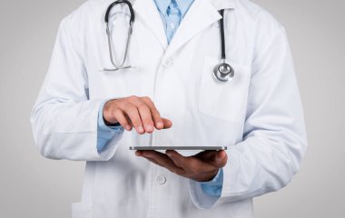 Profesyonel doktorların üst vücudu, steteskop ile beyaz önlük giyip, dijital tablet tutuyorlar. Tıbbi teknik terfiler için uygun..