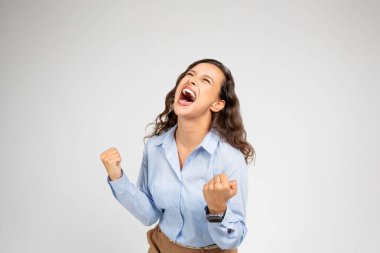 Kızgın, mutsuz, ümitsiz, depresyonda olan, resmi giyimli genç Avrupalı kadın çığlıkları, yumruklarıyla çılgına dönmüş, gri arka plan stüdyosunda izole edilmiş. İş sorunları, stres, baskı ve son teslim tarihi