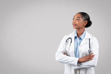 Beyaz labaratuar önlüklü, özgüvenli Afro-Amerikan bin yıllık doktor, düşündü ki, boş alana bakın, gri stüdyo arka planında izole edilmiş. Tıbbi reklam ve teklif, sağlık hizmetleri.